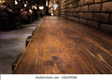 Empty Wood Table Top Of Bar With Blur Of Cafe Restaurant In Dark Night Background/selective Focus .For Montage Product Display