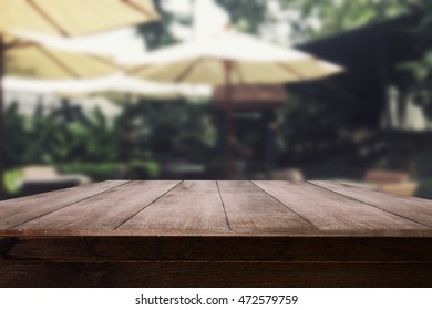 Empty Wood Table Top With Blur Outdoor Coffee Shop With Nature View For Display Your Product Or Advertise Montage.