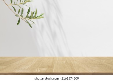 Empty wood table top and blurred white wall in garden background with Green leaves - can used for display or montage your products.