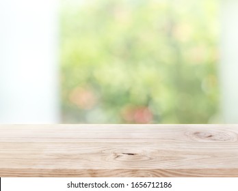 Empty wood table top on blur abstract green garden from window view in the morning. For montage product display or design key visual layout
