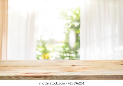 Empty of wood table top on blur of curtain window and abstract green from garden with sunlight .For montage product display or design key visual layout