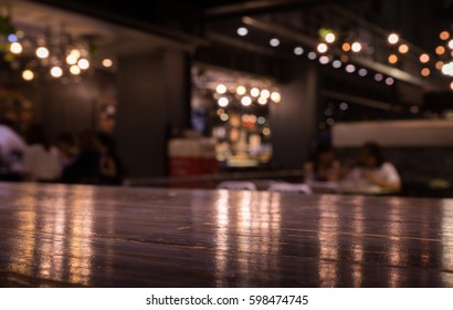 Empty Wood Table Top On Blur Cafe (restaurant) In Dark Night With Light Background/selective Focus.For Montage Product Display