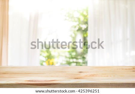 Empty of wood table top on blur of curtain window and abstract green from garden with sunlight .For montage product display or design key visual layout