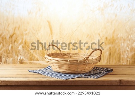 Empty wooden basket on table with tablecloth over wheat field background.  Jewish holiday Shavuot mock up for design and product display.