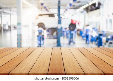 Empty Wooden Board Or Table And Abstract Blurred Background Of Car Technician Repairing The Car In The Shop. Free Space Can Be Used For Photo Montage Or Product Display Design And Advertising