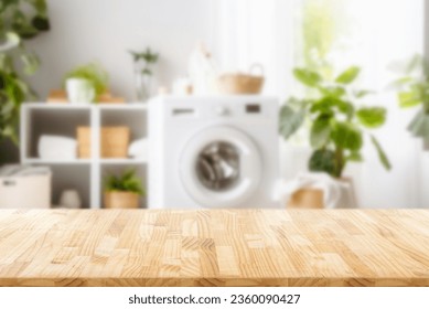 Empty wooden board with towels on blurred background of washing machine in home laundry. Place for product mounting and advertising