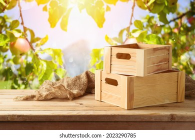 Empty wooden box on rustic table with sackcloth over apple tree background.  Autumn mock up for design and product display.
