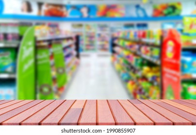 Empty Wooden Counter With Blurred Background Of Various Goods On Shelves Inside Of Convenience Store