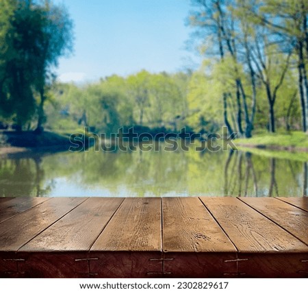 An empty wooden countertop on a blurry natural background. Spring, summer background. Bokeh. A sunny day. Park, river, trees. Space for copying. backdrop