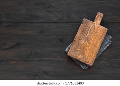 Empty Wooden Cutting Board On Black Wooden Kitchen Table, Top View, Flat Lay. Wooden Platter, Copy Space.