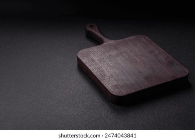 Empty wooden cutting board with spices, salt and herbs on dark concrete background - Powered by Shutterstock