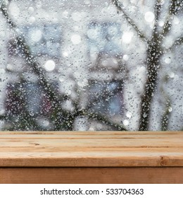 Empty Wooden Deck Table Over Wet Glass Window. Rainy Weather Concept. Background For Product Montage Display