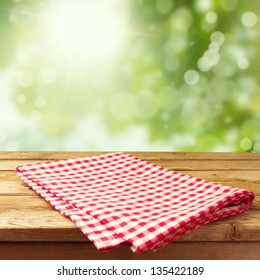 Empty Wooden Deck Table With Tablecloth Over Bokeh Background