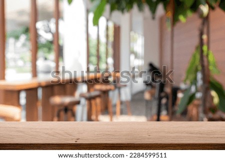 Empty wooden desk with blurred background of coffee shop or bistro cafe.