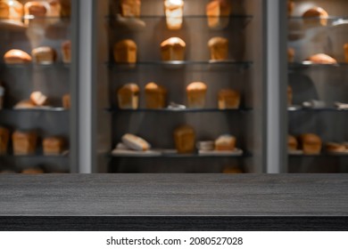 Empty Wooden Desk With Blurry Background Of Bakery Shop.