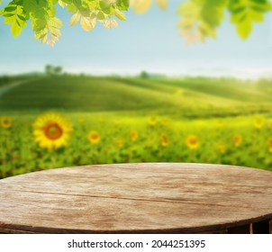 empty wooden desk with blurry Sunflower field against tea plantation on hill and leave as frame Product display stand