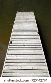 Empty Wooden Dock With Metal Cleats On Muddy Water.