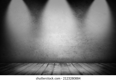 Empty wooden floor and blank grey concrete wall in spotlit lights interior garage studio room. Copy space or product display.
