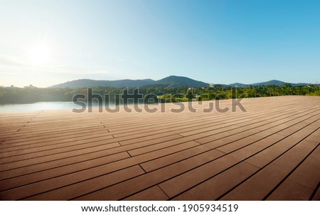 Empty wooden floor in front of
lake view background during sunrise.