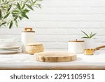Empty wooden pedestal on kitchen table before white brick wall