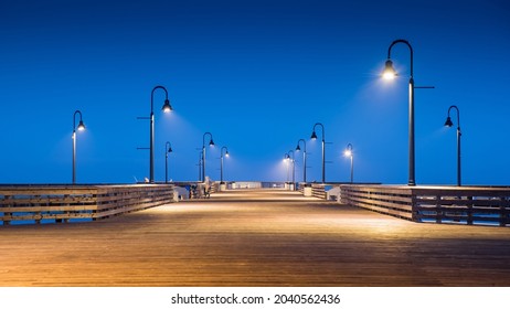 Empty Wooden Pedestrian Bridge With Illuminated Street Light During Twilight Time At Pismo Beach Pier. West Coast Tourist Attraction In California, USA.