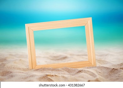 Empty wooden picture frame on the beach sand, summer concept.