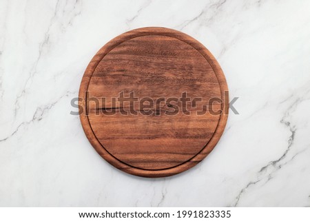 Empty wooden pizza platter set up on marble stone kitchen table. Pizza board on white marble background flat lay and copy space.