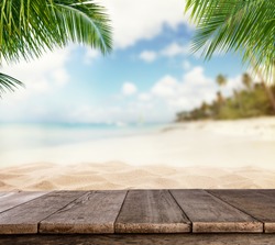 背景上有模糊沙滩的空木板，可用于产品放置，前台棕榈叶