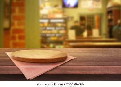 Empty wooden plate on the table with the restuarant soft blurry background, of free space for your copy and branding. Use as products display montage. Vintage style concept.
