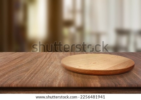 Empty wooden plate on wood table. Soft blurry background, of free space for your copy and branding. Use as products display montage. Vintage style concept.