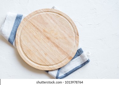 Empty Wooden Platter With Napkin On White Stone Table, Top View, Copy Space. Wooden Cutting Board Over White Concrete Background.