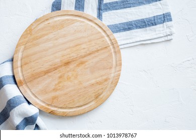 Empty Wooden Platter With Napkin On White Stone Table, Top View, Copy Space. Wooden Cutting Board Over White Concrete Background.