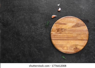 Empty Wooden Round Board On Black Stone Kitchen Table, Top View, Flat Lay. Wooden Pizza Platter, Copy Space.