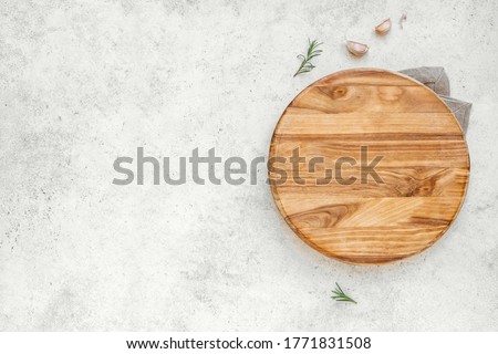 Empty wooden round board on white stone kitchen table, top view, flat lay. Wooden pizza platter, copy space.