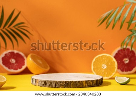 Empty wooden round podium on colorful yellow and orange background surrounded by citrus fruits. Display, pedestal for the presentation of cosmetic products, drinks