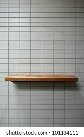 Empty Wooden Shelf On The Tile Wall.