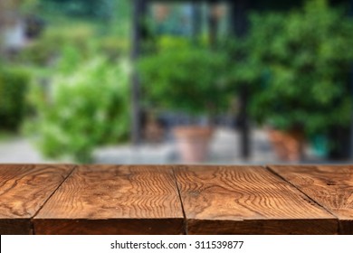 Empty Wooden Table Against Summer Backyard Or Patio With Green Plants On Background