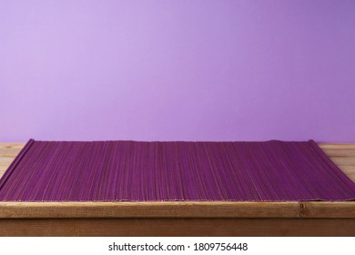 Empty Wooden Table With Bamboo Mat Over Purple Background. Kitchen Or Restaurant Counter Mockup For Design