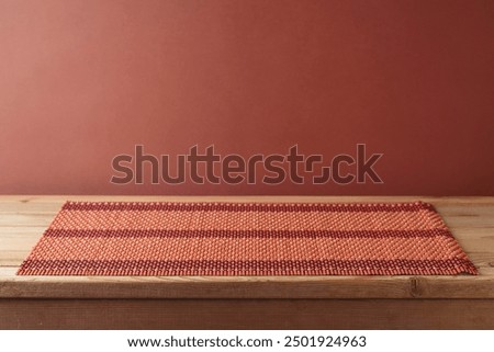 Empty wooden table with bamboo place mat over brown wall background.  Kitchen mock up for design and product display