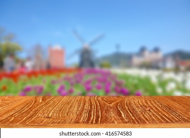 Empty wooden table with blur image of tulip fields