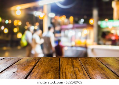 Empty Wooden Table And Blurred Image Of People At The Street Food Shop At Night