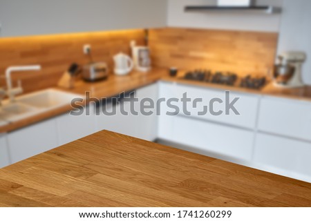 Empty wooden table or countertop top corner with blurred white modern kitchen background. 
