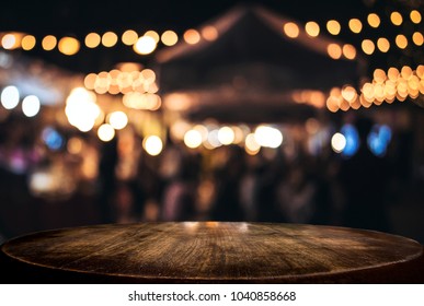 Empty wooden table in front of abstract blurred festive background with light spots and bokeh for product montage display of product.