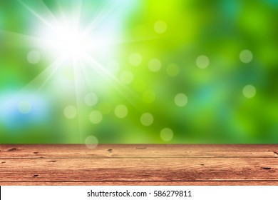 empty wooden table in front of blurred nature background, sunshine in springtime, bokeh lights, blurry springtime or summertime concept