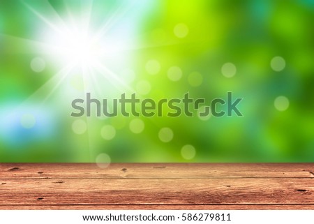 empty wooden table in front of blurred nature background, sunshine in springtime, bokeh lights, blurry springtime or summertime concept