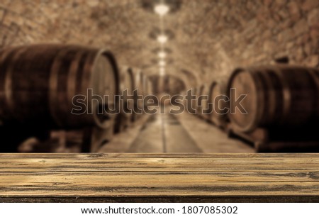 Empty wooden table in front of a wooden wine barrels in wine cellar. Concept Product Banner  Сток-фото © 