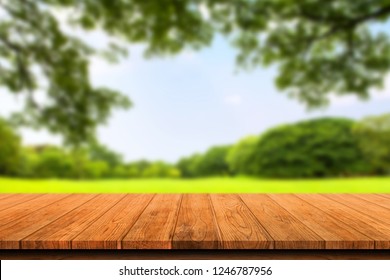 Empty wooden table isolated on blurred green nature background. For your product placement or montage with focus to the table top in the foreground. Empty wooden brown shelf. shelves