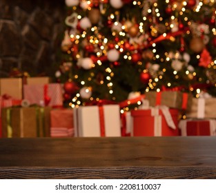 Empty wooden table on the background of a Christmas tree with beautiful toys in the form of balls,golden bokeh and boxes with gifts.Ready for product montage. Copy space. Mockup - Powered by Shutterstock