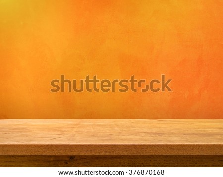 Empty wooden table on orange textured wall