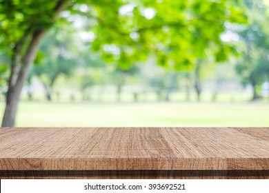 Empty wooden table over blurred tree with bokeh background, for product display montage